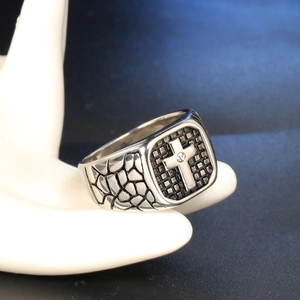 Close-up of vintage stainless steel cross ring with cubic zirconia and textured patterns