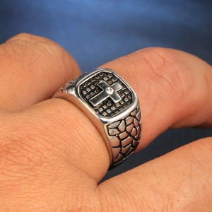 Macro detail of men's stainless steel signet ring with cross engraving and small diamond