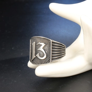 Macro shot of punk style steel shield ring with number 13 on model hand