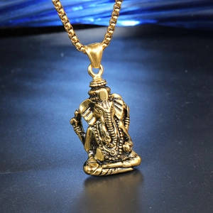 Macro d'un pendentif Ganesha doré aux détails gravés sur une chaîne à mailles