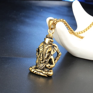 Gros plan détaillé du pendentif Ganesha doré avec gravures fines sur une chaîne en or