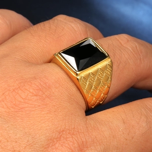 Dettaglio anello vintage da uomo dorato con gemma nera rettangolare e trama a rilievo