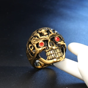 Gothic punk men's skull ring in gold finish with red rhinestone eyes on a model hand