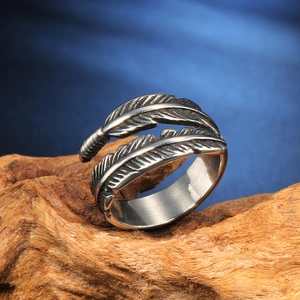 Vintage retro feathered open ring in oxidized stainless steel on a wooden stand