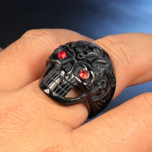 Macro view of punk skull ring with red zircon eyes on hand in dark aesthetic setting