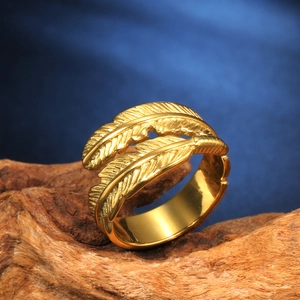 Vintage gold feather wrap ring with detailed layered textures on wood surface