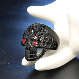 Detail view of gothic skull ring in matte black steel with vibrant red rhinestone eyes