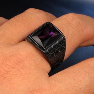 Dettaglio anello vintage dorato con pietra viola rettangolare e trama a rombi