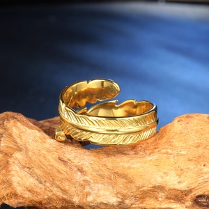 Macro shot of gold feather ring detail showing intricate carving on natural wood