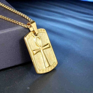 Detail of golden Ankh pendant necklace with polished relief on a textured blue background