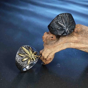 Retro stainless steel leaf rings for men in black and silver finishes on wood