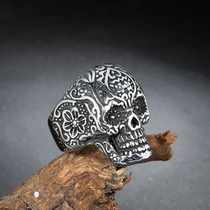 Vintage punk skull ring for men with floral reliefs on a weathered wooden stand