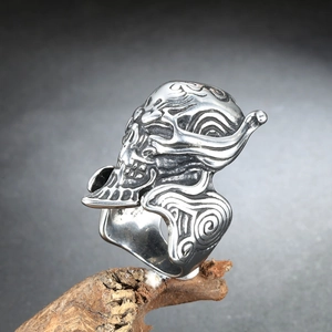 Macro detail of gothic skull ring with wavy engravings on rustic wood background