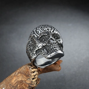 Macro shot of silver skull ring with intricate floral carvings on vintage dark wood