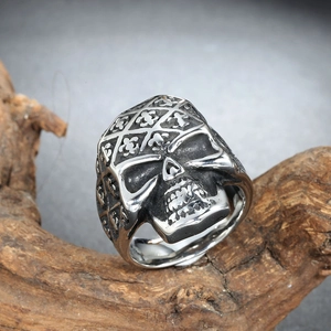 Detailed macro view of punk skull ring with fleur-de-lis patterns on a wood surface