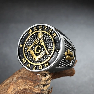 Vintage stainless steel Master Mason Freemasonry ring with gold accents on rustic wood