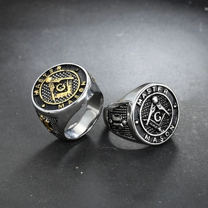 Polished stainless steel Master Mason ring with gold accents on stone texture background
