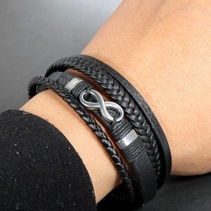 Detail of multi-layer men's black leather bracelet with silver infinity symbol and magnetic clasp
