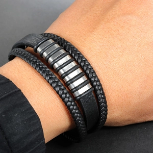 Close-up of men's multi-layer braided leather bracelet with silver metal charms