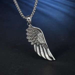 Détail du pendentif étoile et aile argentée vintage avec des textures noires sur chaîne box