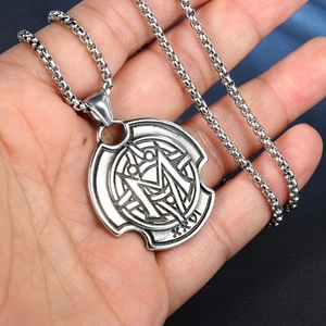 Détail du pendentif rond en acier inoxydable avec motif M et chiffres romains