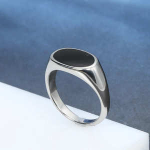 Polished stainless steel signet ring with oval black enamel inlay for men on a white block