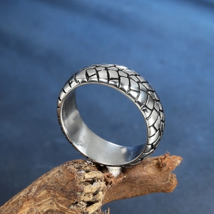 Men's stainless steel wide band ring with embossed dragon scale texture on wood base