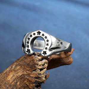 Retro stainless steel horseshoe ring with engraved stars on textured wood surface