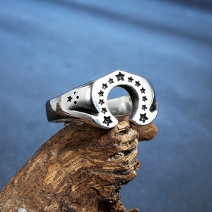 Retro stainless steel horseshoe ring with star patterns on a rustic wooden base