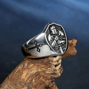 Vintage titanium steel knight signet ring with shield cross on a rustic wood background