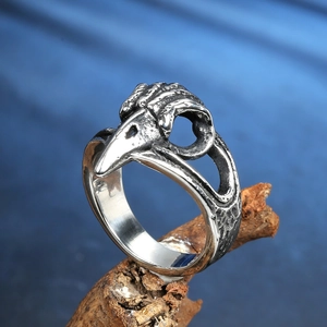 Gros plan sur la bague crâne de corbeau viking en acier inoxydable sur bois mort