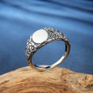 Vintage stainless steel floral engraved ring shown from a 45-degree angle on wood