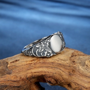Vintage floral stainless steel signet ring with oval face on natural wood background
