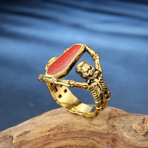 Gothic punk vampire skull ring with a red coffin design on a rustic wood background