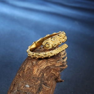 Golden octopus tentacle ring made of stainless steel on rustic wood background