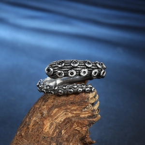 Octopus tentacle ring in vintage stainless steel displayed on a natural wood base