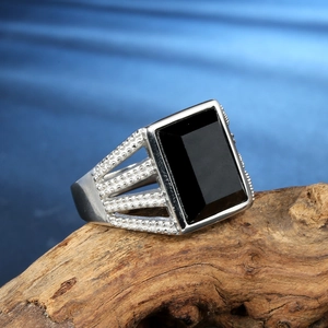 Men's stainless steel ring with rectangular black onyx stone on a rustic wood base