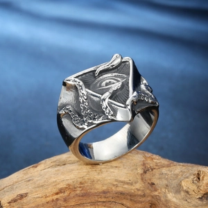 Retro stainless steel ring with Eye of Providence and octopus design on wood background