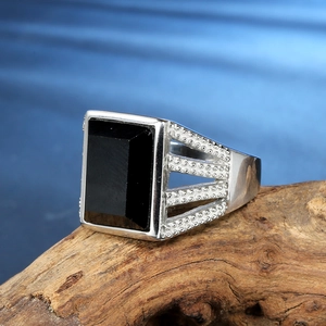 Macro detail of men's stainless steel ring with rectangular black agate stone on wood