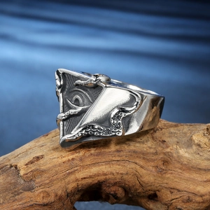 Gothic octopus eye ring with tentacles on wood background in high detail