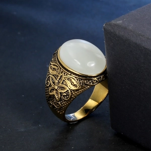 Macro detail of vintage gold ring with large white gemstone and floral butterfly engravings