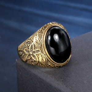Vintage gold-tone ring with black oval stone and floral engravings on textured base
