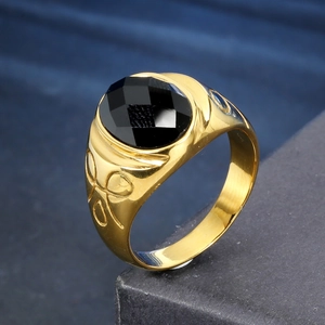 Macro detail of men's wide gold ring featuring an oval black gemstone and geometric textures