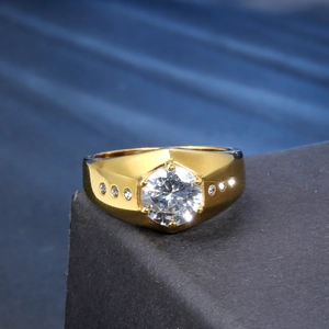 Macro shot of a men's gold ring with a large round zircon and side stones on a platform