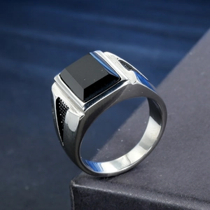 Close-up of punk rock men's ring featuring a square black stone and silver steel band