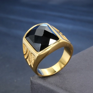 Détail d'une bague dorée vintage pour homme avec pierre noire carrée et motifs de feuilles