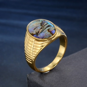 Macro shot of men's gold ring featuring oval abalone shell inlay and ribbed side texture
