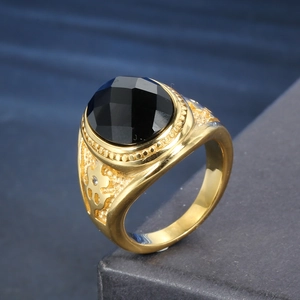 Macro shot of gold stainless steel ring with black gemstone and vintage carving details