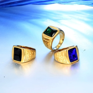 Detalle de anillos dorados grabados con piedras preciosas verdes, negras y azules