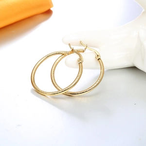 Textured gold hoop earrings for women with minimalist spiral pattern on white model